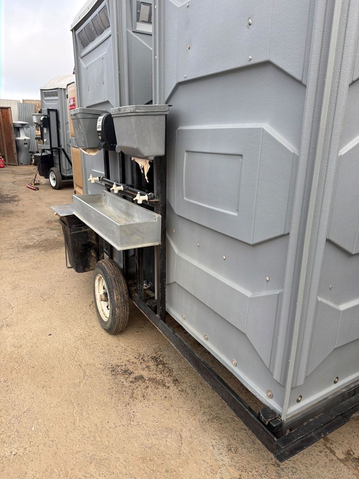 Hand-washing sinks mounted on the side of a field sanitation restroom trailer