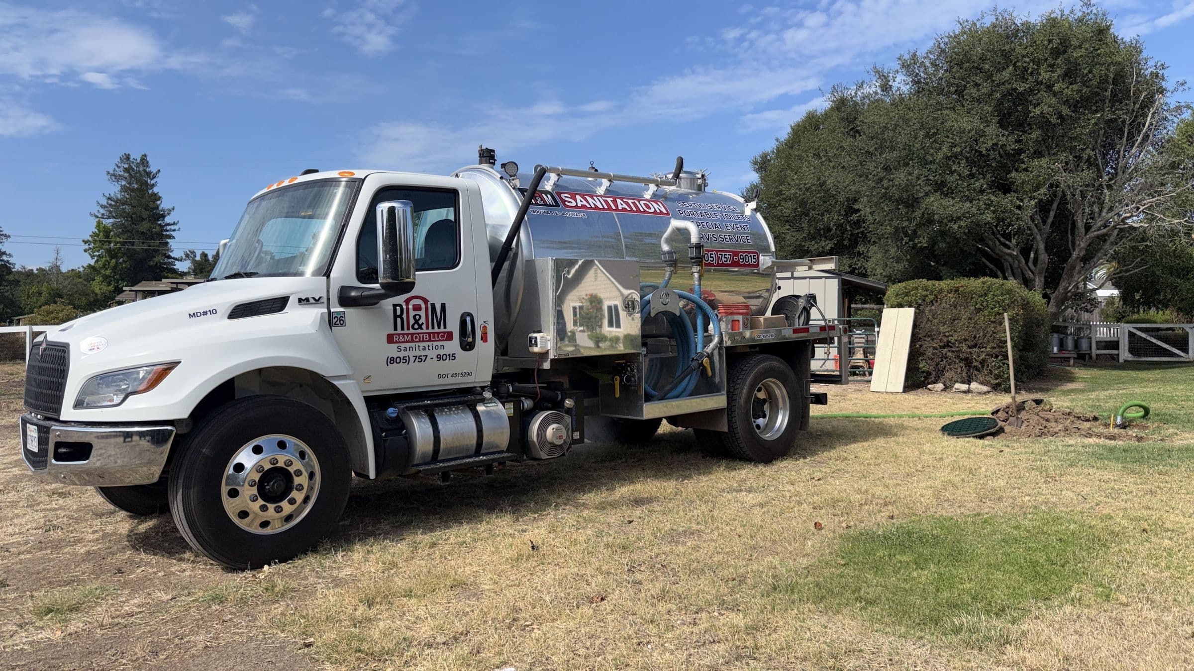R&M Sanitation vacuum pump truck parked on a grassy ranch property